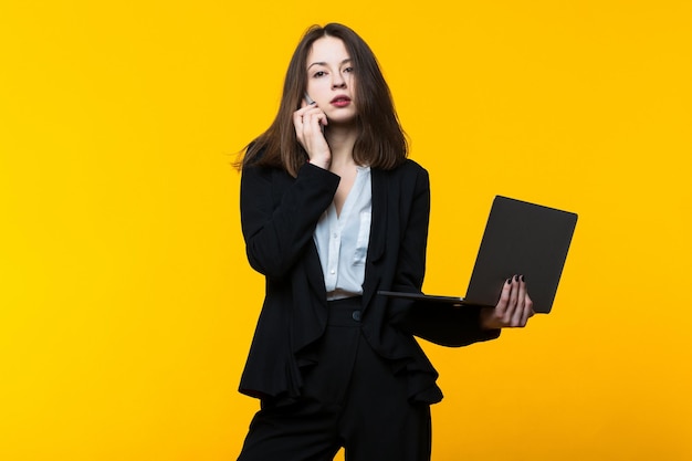 Business woman phone conversation laptop yellow background