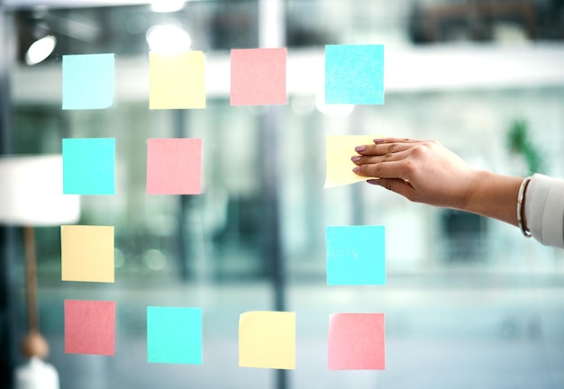 Business woman planning company growth and strategy by arranging sticky notes and managing her schedule Closeup of an employee brainstorming ideas for a startup mission or vision