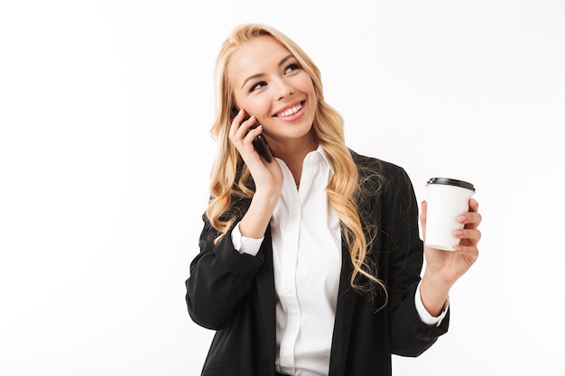 Business woman posing isolated over white wall holding coffee cup talking by phone.