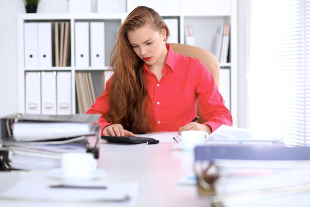 Photo business woman in red blouse making report calculating or checking balance