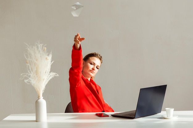 Business woman in a red suit throws a paper plane into the air office lifestyle concept