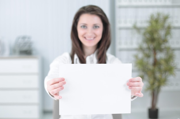 Business woman showing blank sheetsitting behind a Desk