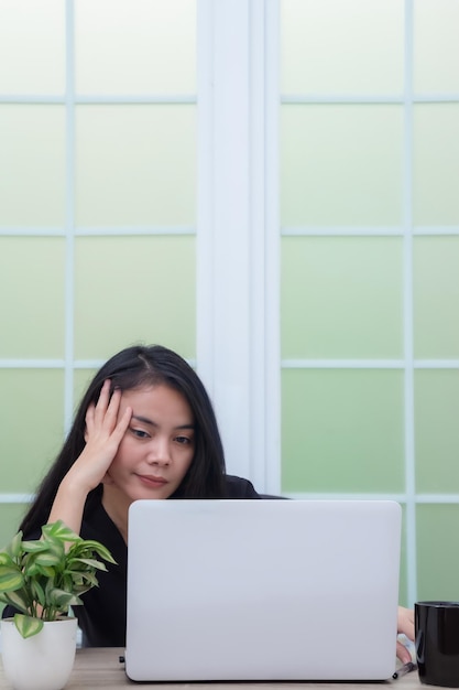 Business woman sitting on chair looking at laptop screen with lazy expression