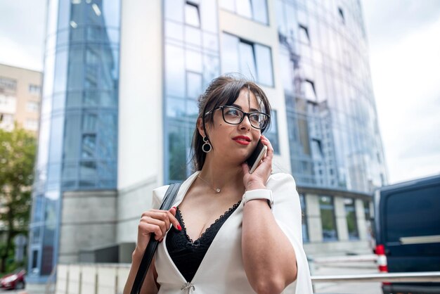 Business woman standing on street in the city center using mobile phone during break at work