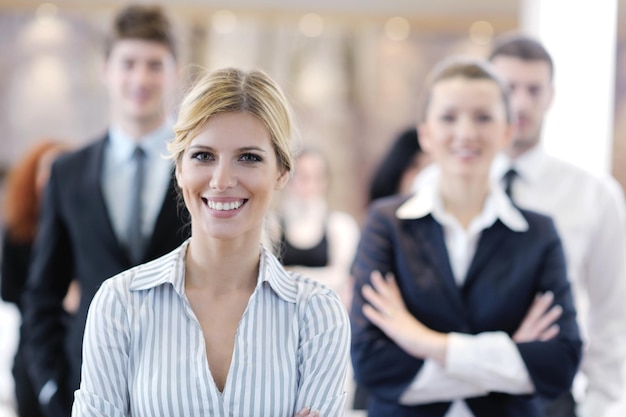 Photo business woman standing with her staff in background at modern bright office conference room