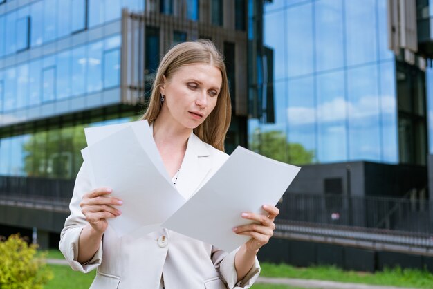 Business woman successful executive director reads paper documents in a light jacket standing on the...