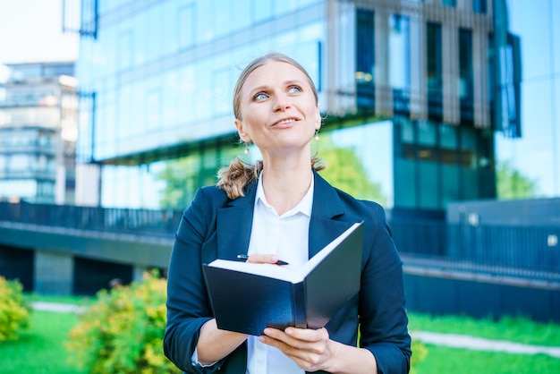 Business woman in suit is in city center against backdrop building writes