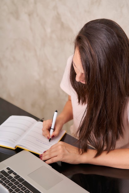 Business woman taking notes at home desk