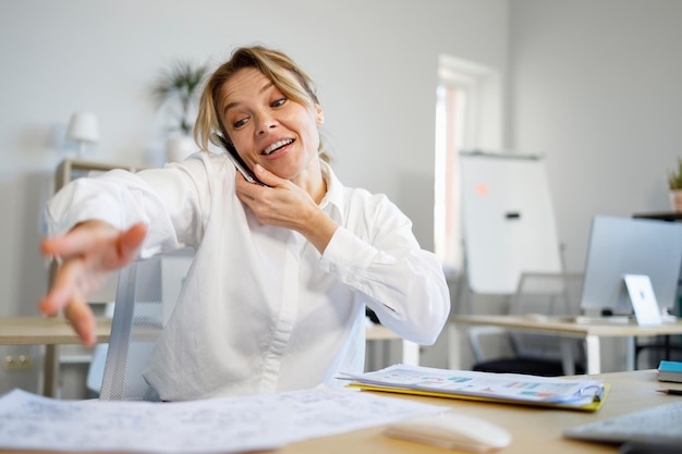 Business woman talking on the phone and looking for documents on the table