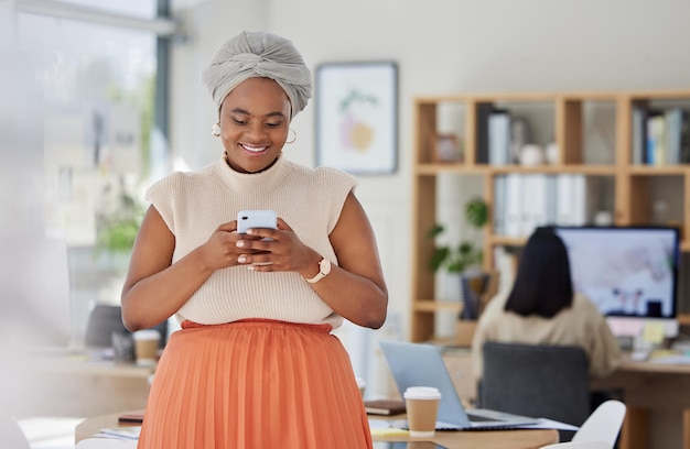 Business woman typing on social media on phone at work reading email and networking with people online on a smartphone in an office Happy black woman in communication on internet with technology