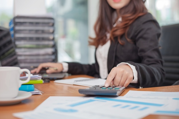 Business woman using calculator and writing make note with calculate.