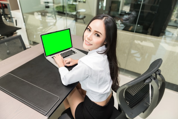 business woman using a laptop computer at office, smiling face, clipping path on screen