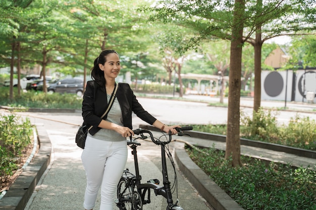 Business woman walks on her folding bike while receiving a telephone call