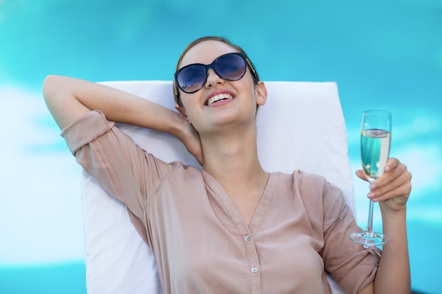 Business woman with a glass of champagne relaxing on sun lounger