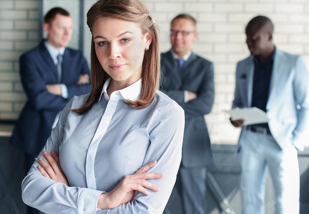 Business woman with her staff people group in background at modern bright office indoors