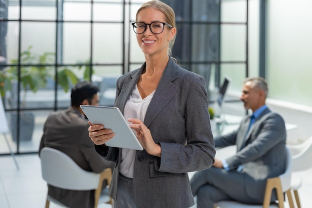 Business woman with her staff people group in background at modern bright office indoors