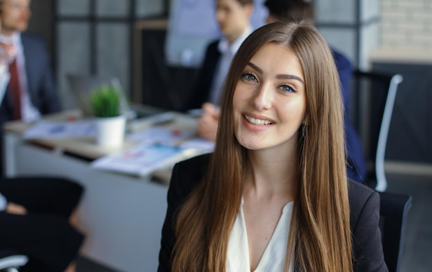 Business woman with her staff people group in background at modern bright office indoors