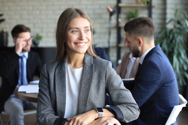 Business woman with her staff, people group in background at modern bright office indoors.