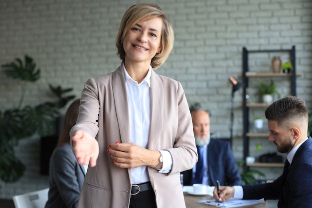 Business woman with an open hand ready for handshake in office.