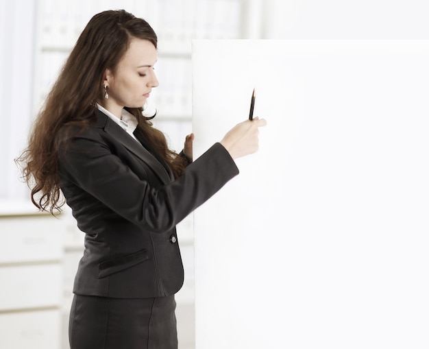 Business woman with a pencil pointing at a blank poster