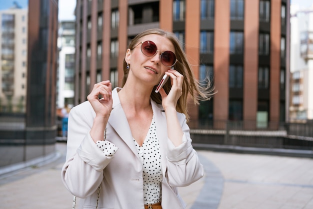 Business woman with phone near office portrait of beautiful smiling girl in fashionable light office...