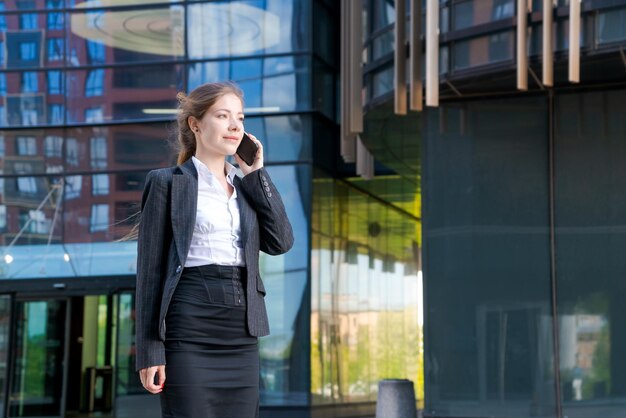 Business woman with phone near office Portrait beautiful smiling girl