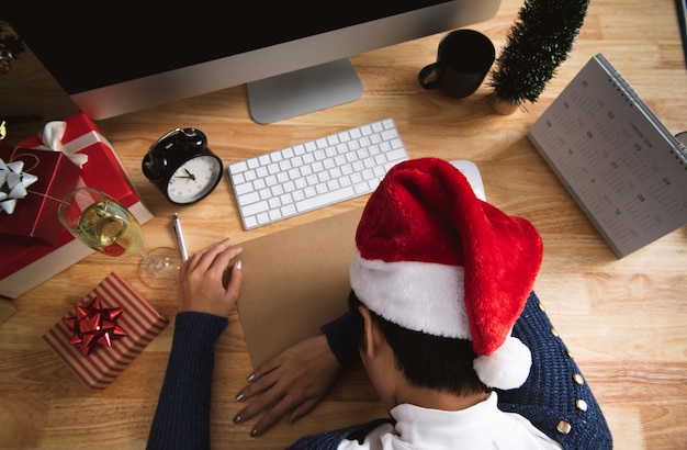 Business woman with santa hat sleeping on desk office after christmas party and happy new year.