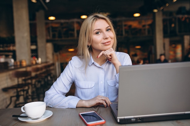 Business woman working on laptop and phone in a cafe