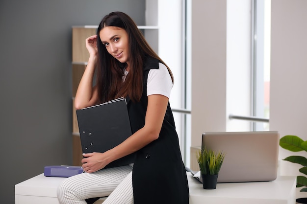 Business woman working in the office holding a black folder thinking about development plans solving problems