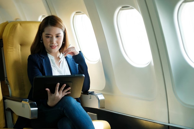 Business woman working on tablet while sitting in airplane