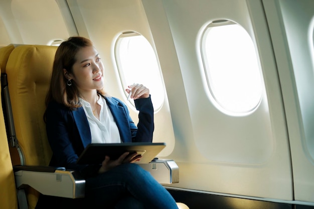 Business woman working on tablet while sitting in airplane