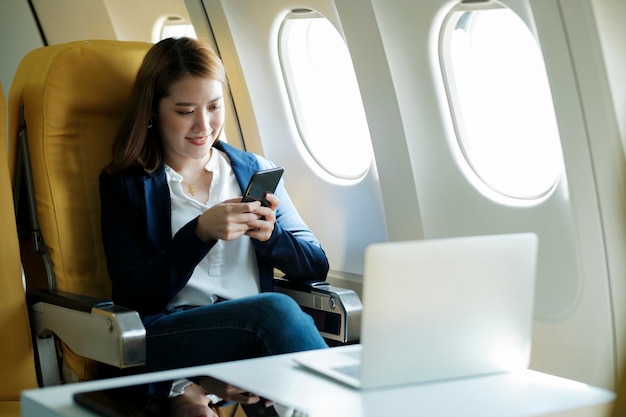 Business woman working using phone while sitting in airplane