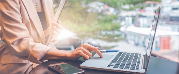 Business woman working with a laptop computer and uses a cell phone in the office.web banner.