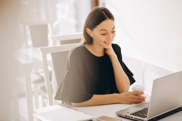 Business woman working with laptop in a white cafe