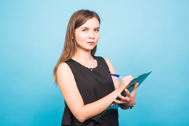 Business woman writing on a clipboard, isolated on a blue background.