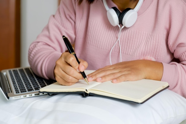 Business women bookkeeper hand holding pen and use laptop doing account for paying tax on on the bed, work from home concept.