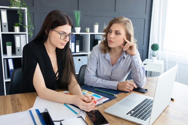 Business women at office desk working together on laptop, teamwork concept