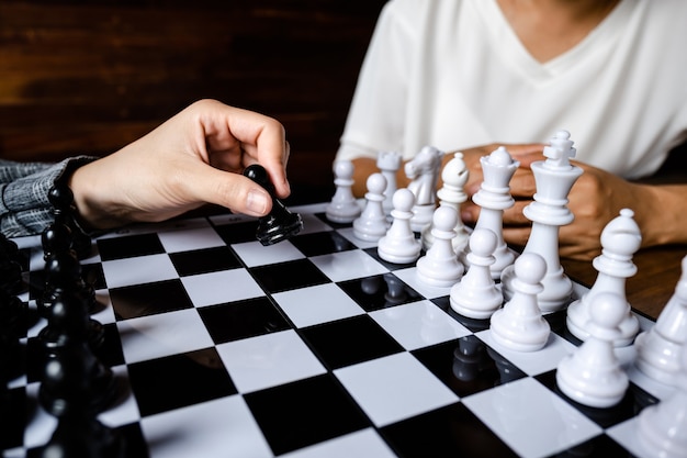 Business women play chess on board challenges planning business strategy to success concept