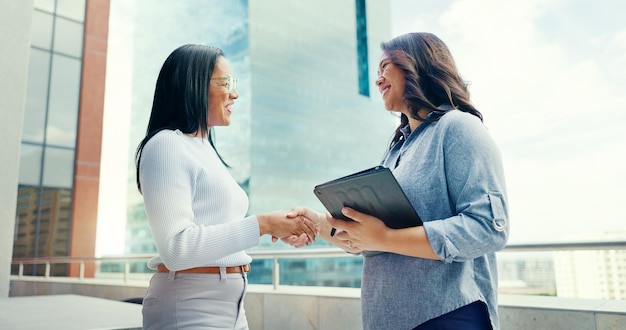 Business women on rooftop and handshake with tablet collaboration and partnership for new project Corporate female employees talking and coworkers outdoor digital planning and website launch