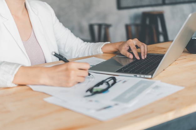 Business women sitting on a laptop and checking business graph documents, working in financial transactions, accounting