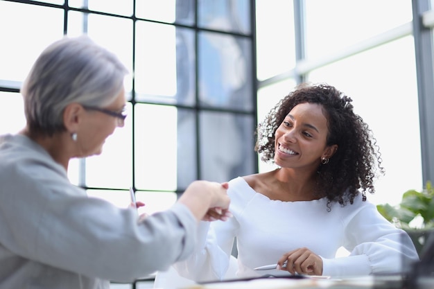 Business women smile and shaking hands at a table in the boardroom in the office