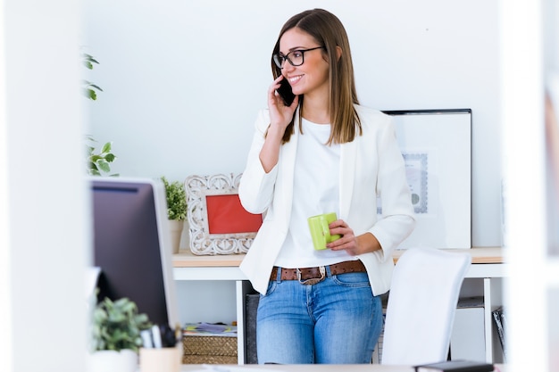 Business young woman using her mobile phone in the office.