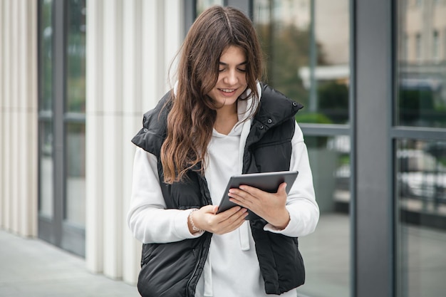 Business young woman with a tablet on the background of the building