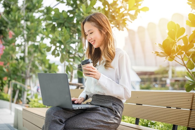 business young woman working laptop outdoor corporate building exterior