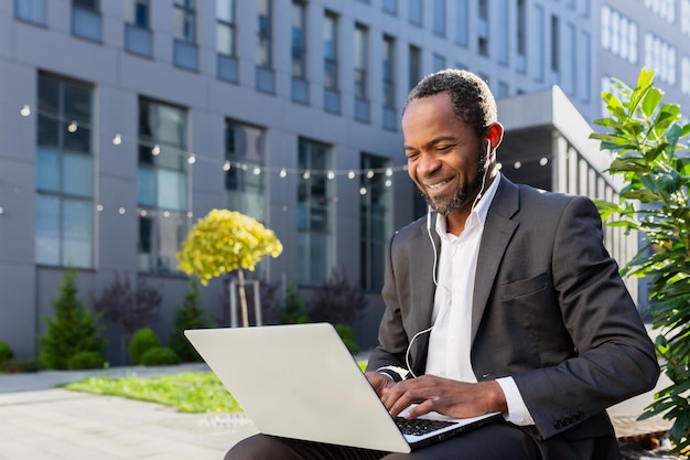 Businessman african american freelancer sitting near office center orking online on laptop and