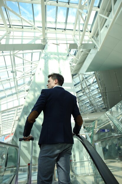 Businessman at the airport going down the escalator.