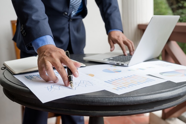 Businessman analysis graph with laptop at the home office for setting challenging business goals