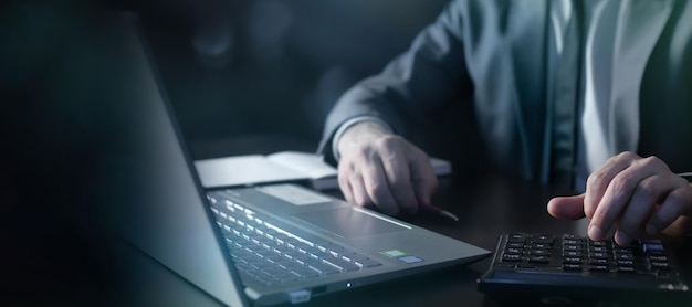 Businessman analyzing data using laptop and calculator