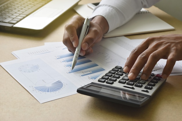 Businessman analyzing financial graphs and charts report on desk in office. 