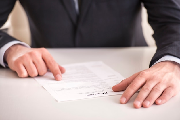 Businessman analyzing resume at desk in office.